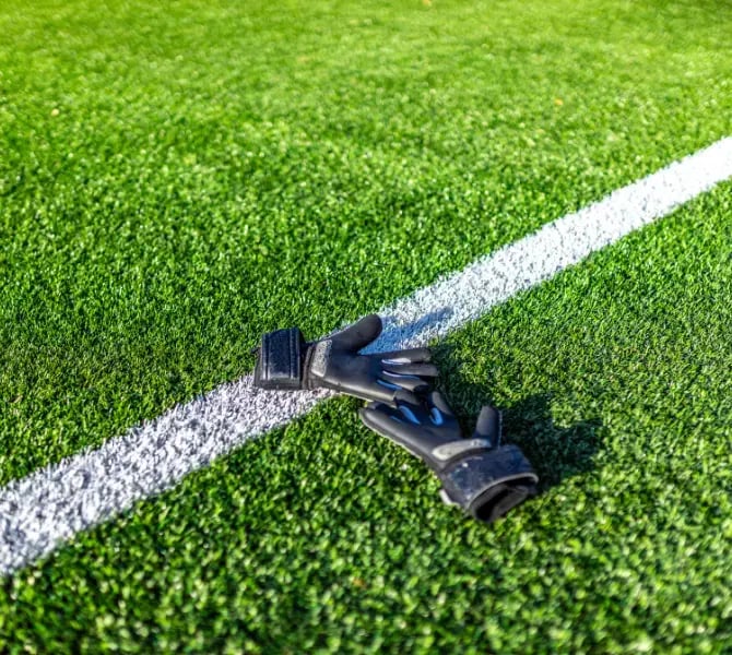 goalkeeper gloves resting on synthetic turf field